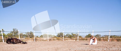 Image of young woman training horse outside in summer