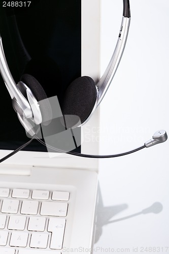 Image of headset keyboard notebook laptop in office on table desk