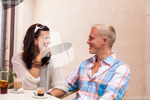 Image of happy young couple sitting outside cafe restaurant drinking coffee 