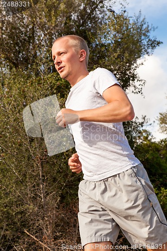 Image of athletic man runner jogging in nature outdoor