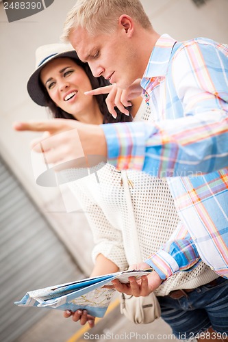 Image of young attractive tourist couple with city map in summer