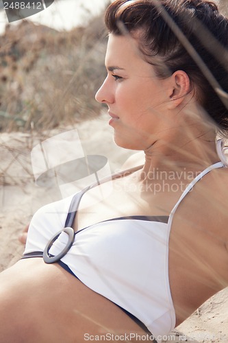 Image of happy young woman sitting in sand dunes beach 