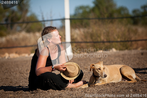 Image of smiling blonde woman sitting outdoor with her dog