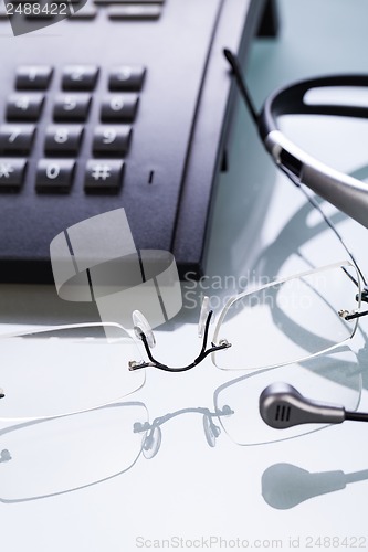 Image of working place office desk table headset glasses telephone