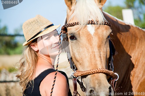 Image of young woman training horse outside in summer