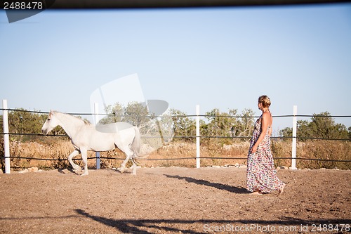 Image of young woman walking a road with horse