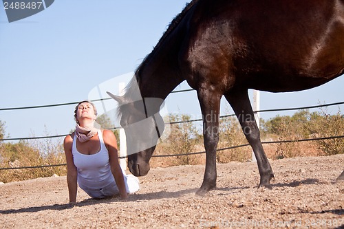 Image of young woman training horse outside in summer