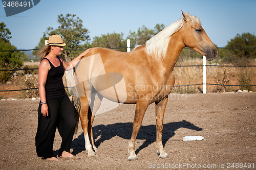Image of young woman training horse outside in summer