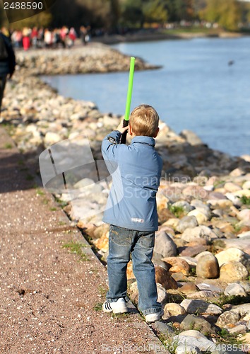 Image of Boy playing on the river bank with a sword
