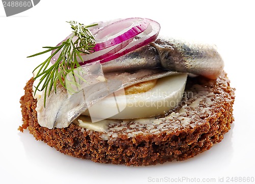 Image of brown bread canape with anchovies decorated with red onion and d