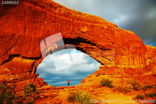 Image of Woman staying with raised hands inside an Arch