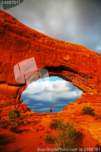 Image of Woman staying with raised hands inside an Arch