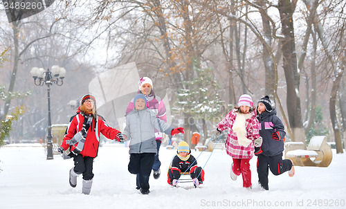 Image of Group of children and mother playing on snow in winter time