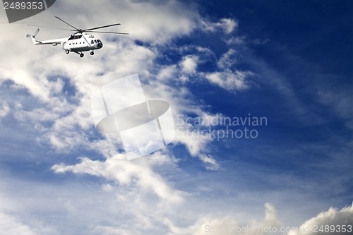 Image of Helicopter in blue sky with clouds