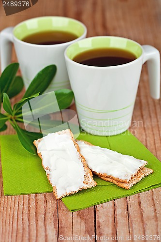 Image of two cups of tea and crackers with cream cheese 