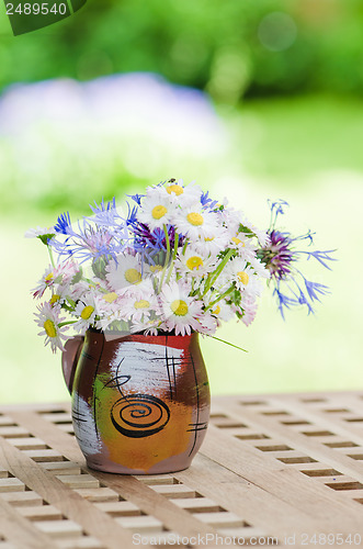 Image of Bouquet of daisies on the table in the garden. Summer background