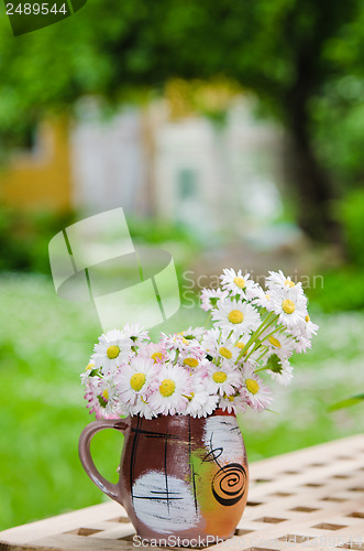 Image of Bouquet of daisies on the table in the garden. Summer background