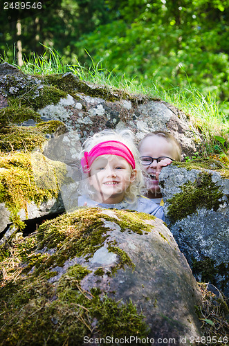 Image of Young children, the boy with the girl hid among the rocks