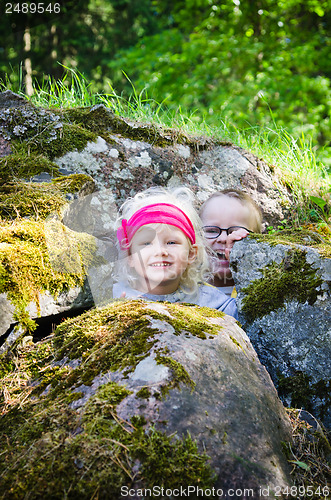 Image of Young children, the boy with the girl hid among the rocks