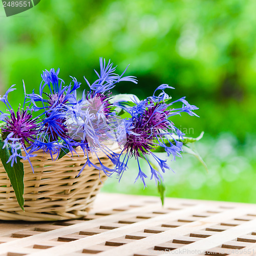 Image of Bunch of cornflowers in a wicker basket. Summer background