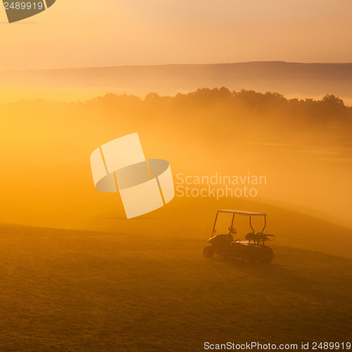 Image of Green golf cart on the empty golf course