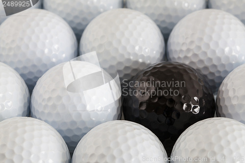 Image of White golf balls and one black ball