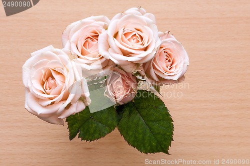Image of pink roses in a vase on a wooden desk