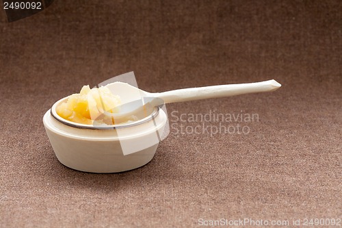 Image of Pot of honey and wooden spoon on a burlap