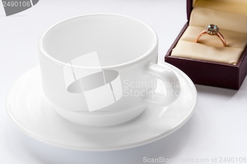 Image of gold ring with a diamond and a cup and saucer