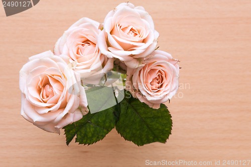 Image of pink roses in a vase on a wooden desk