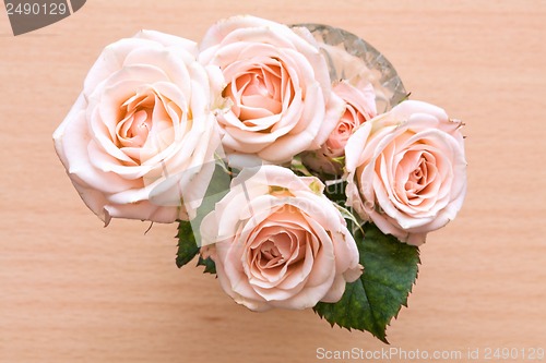 Image of pink roses in a vase on a wooden desk