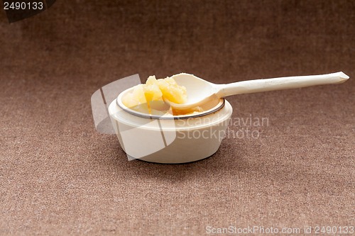 Image of Pot of honey and wooden dipper on a cloth