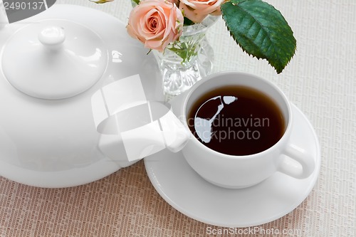 Image of teapot, cup, and  roses on a plate