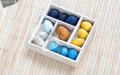 Image of Box with colored nuts on a bamboo napkin