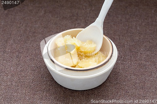 Image of Pot of honey and wooden dipper on a cloth