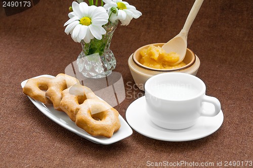 Image of honey cookies, cup and a vase of daisies