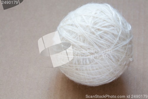 Image of Ball of white wool yarn on cardboard background