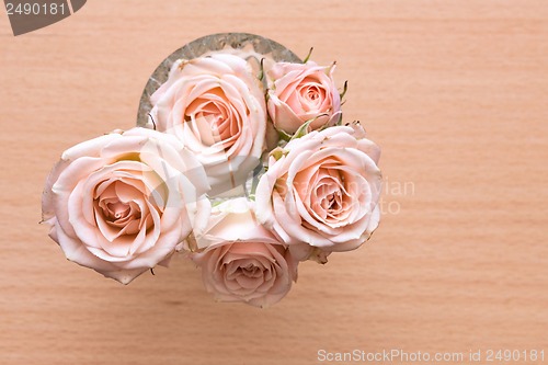 Image of pink roses in a vase on a wooden desk