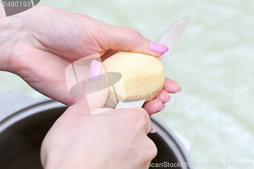 Image of Hands with knife cut the potatoes into the pan