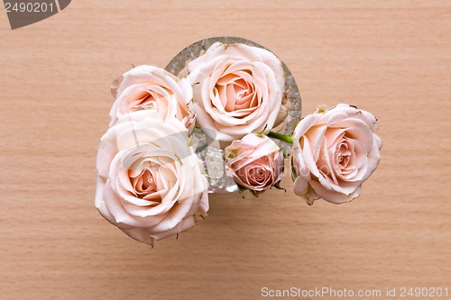 Image of pink roses in a vase on a wooden desk