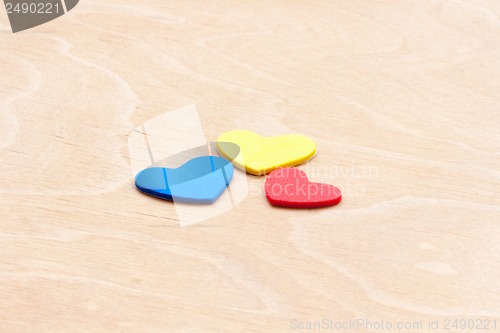 Image of multicolored hearts on a white wooden background