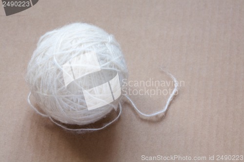 Image of Ball of white wool yarn on cardboard background