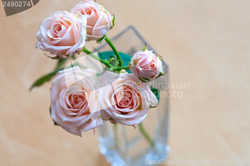 Image of pink roses in a vase on a wooden desk