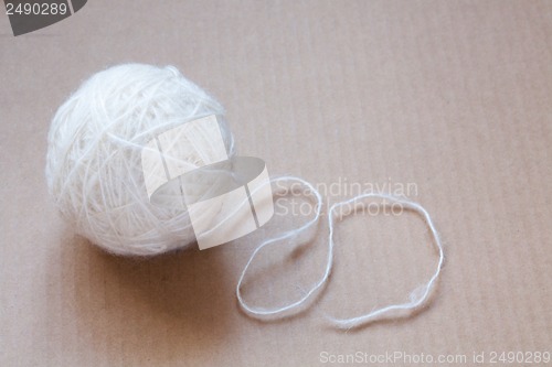 Image of Ball of white wool yarn on cardboard background