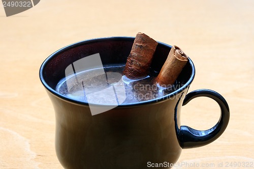 Image of Cup of coffee with cinnamon sticks on wooden table