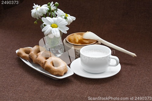 Image of honey, cookies, cup and a vase of daisies