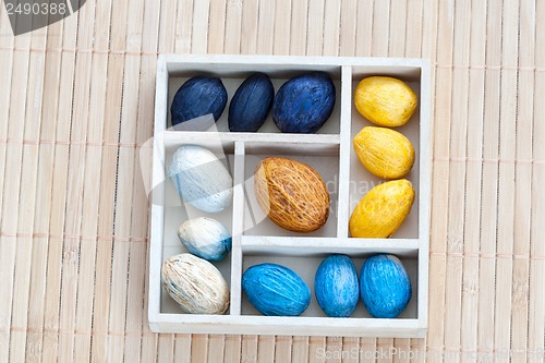 Image of Box with colored nuts on a bamboo napkin