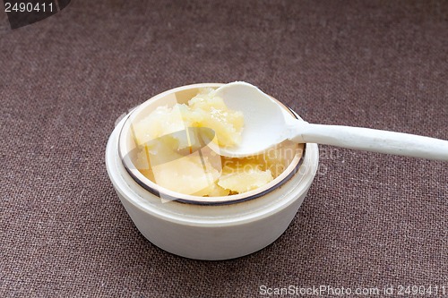 Image of Pot of honey and wooden spoon on a cloth