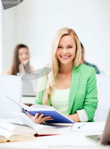 Image of smiling young woman reading book at school