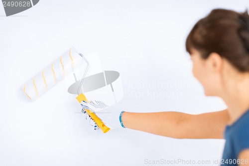 Image of woman with roller and paint colouring the wall